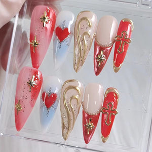 Close-up of ten red and white nail designs with gold accents. The designs include hearts, stars, crosses, and swirls.