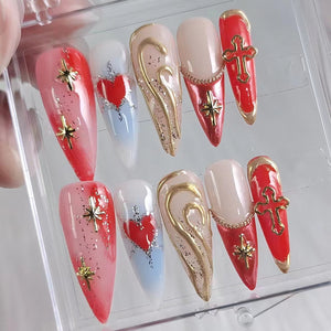 Set of ten false nails with various designs. Some nails feature a red heart, a gold swirl, a red cross, and gold stars.