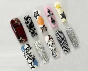 Ten long, artificial fingernails with various designs. The designs include a red and black plaid pattern, a black and white swirl, a black and white yin yang symbol, a black and white skull, a black and white spiral, a black and white cross, a black