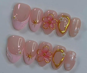 Pink and white nail tips with gold accents and pink flower designs.