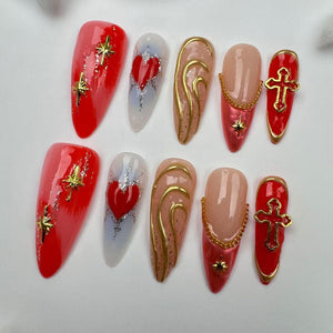 Set of ten red, white, and gold press-on nails with various designs, including hearts, crosses, and swirls.
