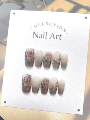 A set of ten false nails with a gradient design. The nails are a light beige color at the base and fade to a darker gray at the tip. Each nail features a hand-painted rose with green leaves.