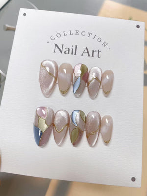 A set of almond-shaped false nails with a shimmering pink base, accented with gold lines and geometric designs in pink, blue, and green. The text "COLLECTION. Nail Art" is printed on the white backgro