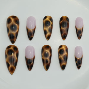 Set of ten almond-shaped false nails. Five nails feature a tortoiseshell pattern in shades of brown and black. The other five nails have a light pink base with a brown tip.
