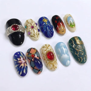 A collection of ten intricately designed nail art pieces. Each nail features unique designs, including gemstones, abstract patterns, and miniature landscapes. Colors range from deep blues and reds to soft pastels and gold accents, showcasing a variet