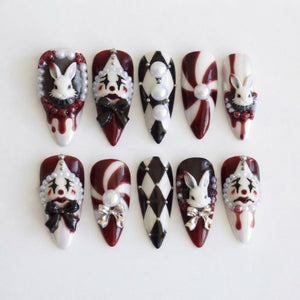 A set of ten almond-shaped press-on nails featuring a dark red, black, and white color palette. Designs include 3D white rabbit heads, clown faces with bows, black and white diamond patterns, and swirling red and white candy stripes.
