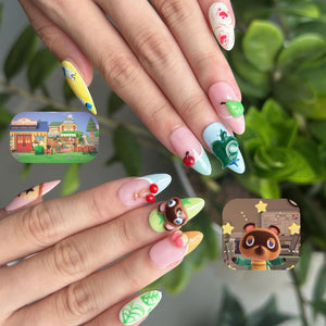 Cozy game inspired press on nails with cute animal, fruit and leaf details in pastel pink, green, blue and yellow on glossy almond shaped nails