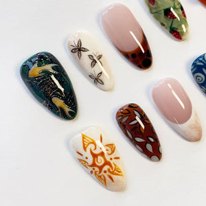 A collection of almond-shaped press-on nails featuring diverse designs including a dark green marble pattern, white nails with black butterflies, a sunburst motif, brown nails with leaf patterns, and French tips with strawberry accents.