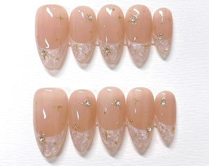 Set of ten nude-colored false nails with a white lace design and gold glitter stars.