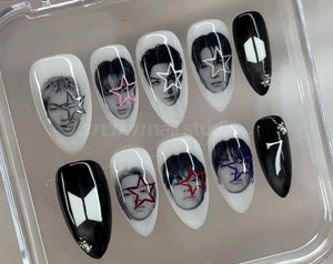A set of ten almond-shaped press-on nails in a clear plastic case. The nails feature black and white portraits of individuals with colorful star overlays, solid black nails with small rhinestones, and