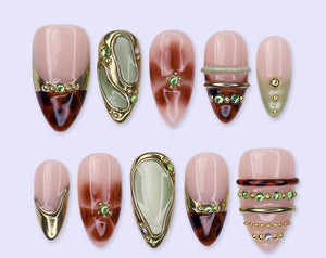 A set of ten almond-shaped press-on nails featuring a mix of designs including tortoiseshell patterns, sage green accents, metallic gold bands, and small green rhinestones. The nails have a glossy fin
