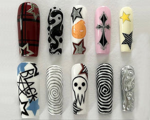 Ten long, almond-shaped false nails with different designs. The designs include a black and white swirl, a black and white checkered pattern, a black and white skull, a black and white cross, a black and white star, a black and white spiral, a black 