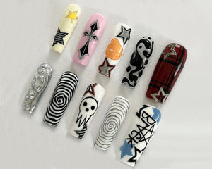 Ten long, white, artificial fingernails with various black and white designs. The designs include a skull, a cross, stars, a yin yang symbol, a spiral, and plaid.