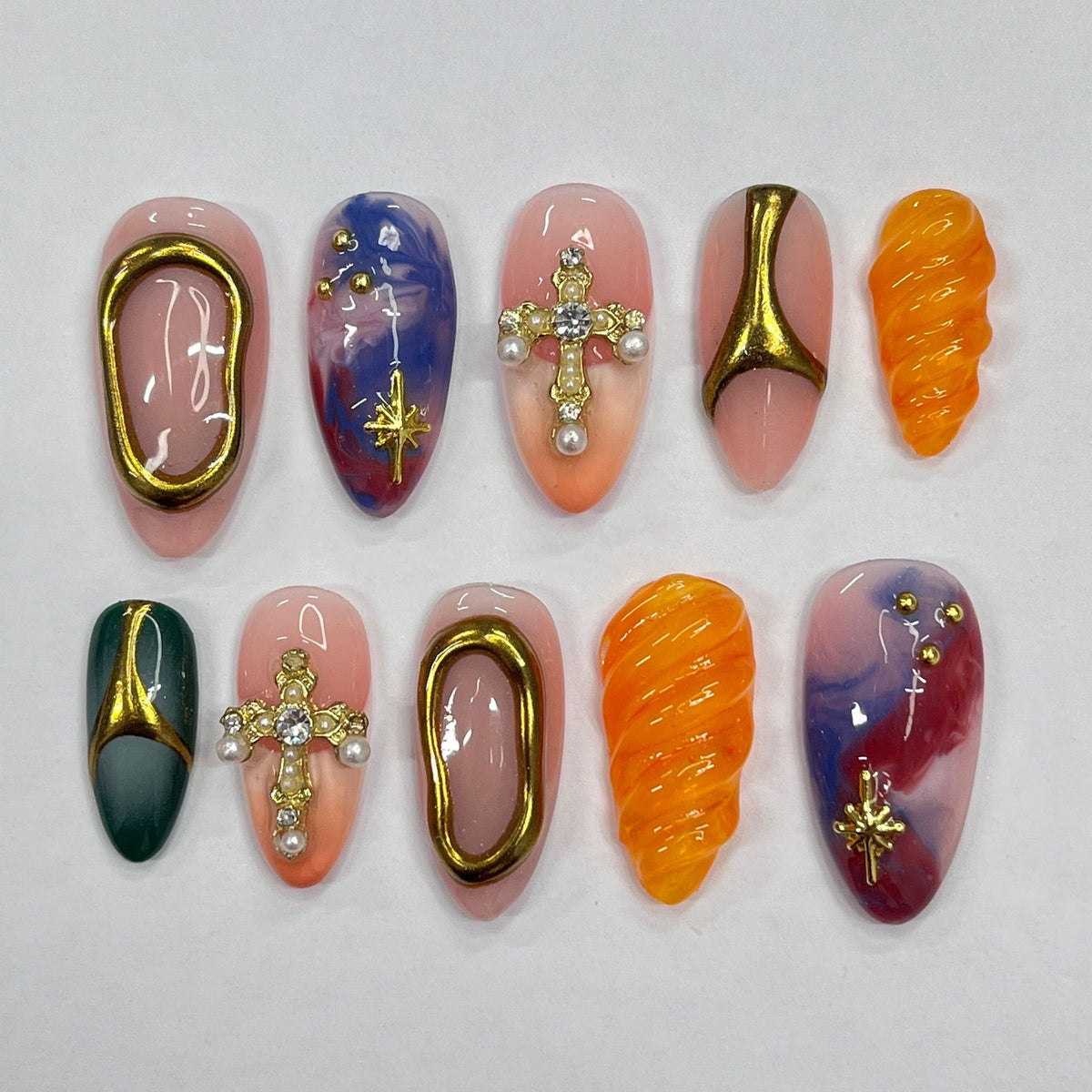 Ten different nail designs featuring a variety of colors, patterns, and embellishments, including gold crosses, swirls, and stars.
