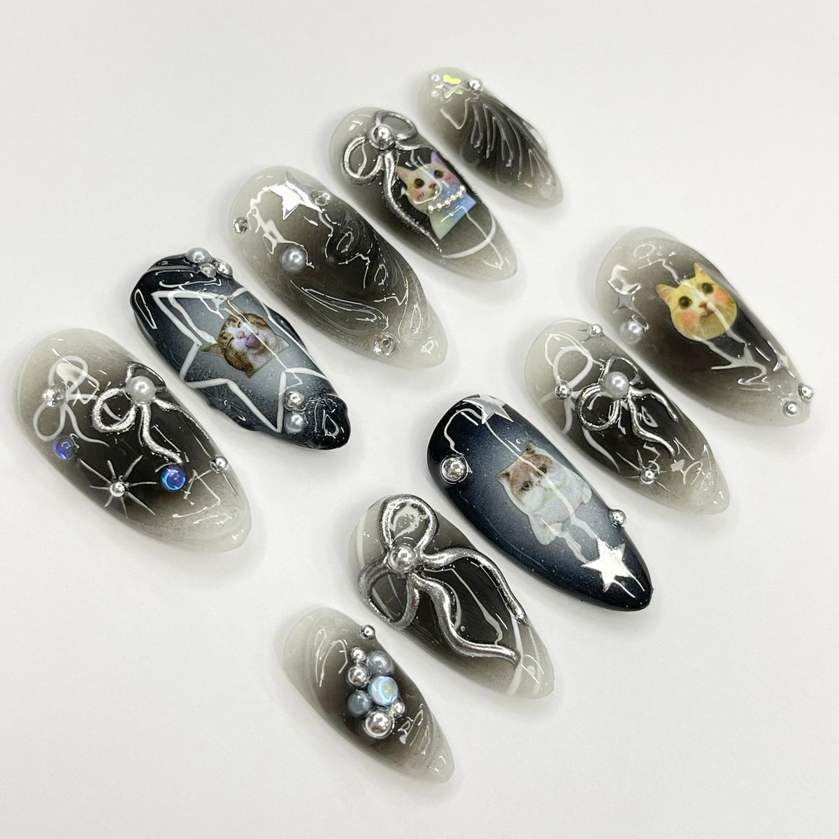 Set of ten black and white ombre nail tips with silver glitter and cat illustrations.