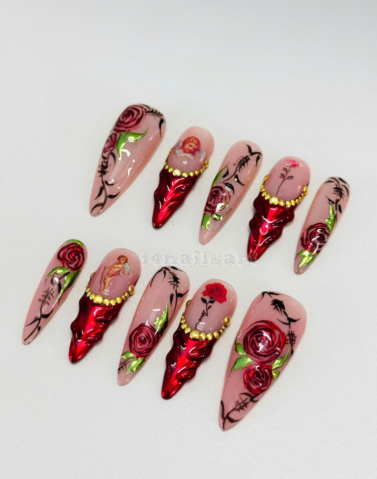 Set of ten long, stiletto-shaped false nails with a pink base and red roses, gold accents, and a cherub design.