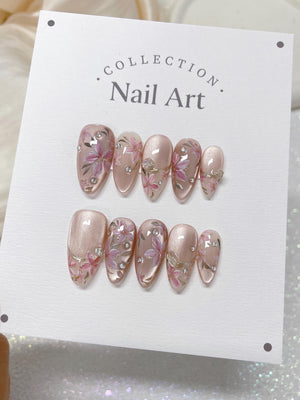 A set of ten pink and white nail tips with floral designs and rhinestones. The nail tips are displayed on a white card with the text "COLLECTION. Nail Art."
