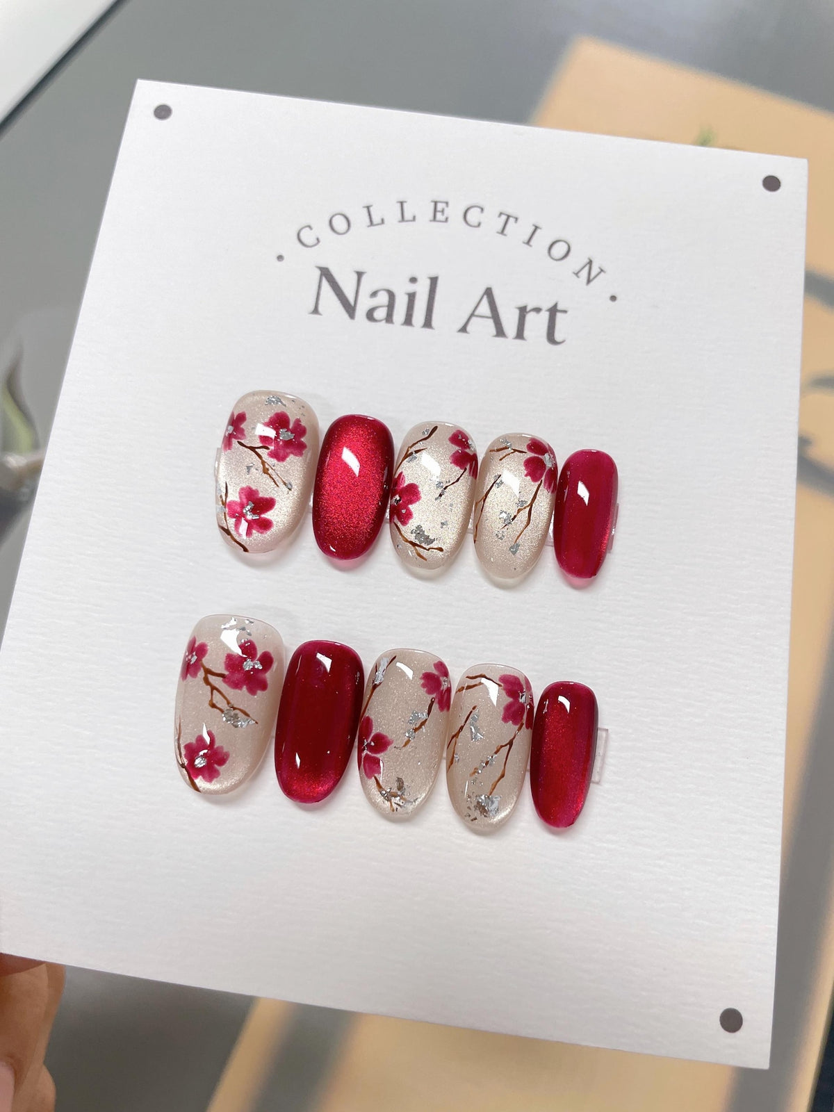 A set of ten red and white nail art tips with a floral design. The tips are arranged in two rows of five. The tips are on a white card with the text "COLLECTION Nail Art."