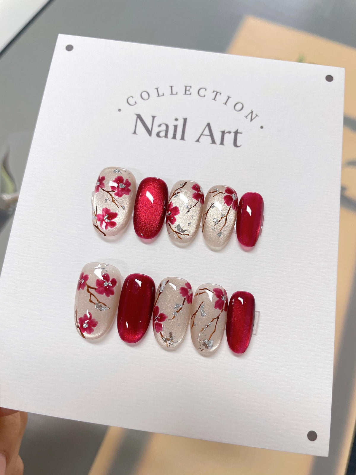 A set of ten red and white nail art tips with a floral design. The tips are arranged in two rows of five. The tips are on a white card with the text "COLLECTION Nail Art."