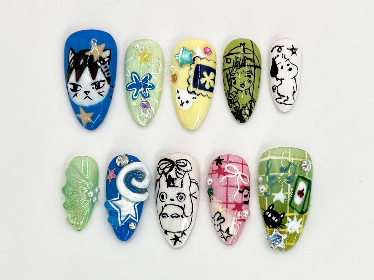 Ten colorful, decorated fake fingernails with various designs, including a cat, a swirl, a cartoon character, and a grid pattern.