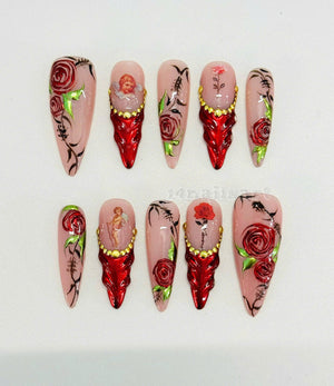 Set of ten long, stiletto-shaped false nails with a pink base and various designs. Some nails feature red roses, a cherub, and gold accents. Others have a red base with gold accents.