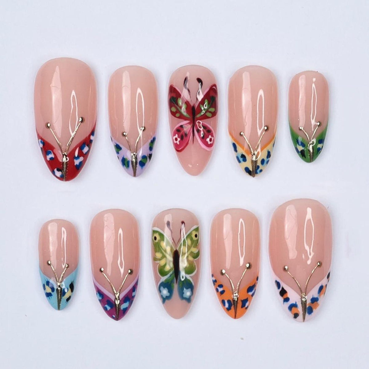 A set of ten artificial nails with a nude base, each adorned with a butterfly design. The butterflies feature vibrant colors like red, green, blue, and orange, accented with gold-colored lines. The nails are oval-shaped.
