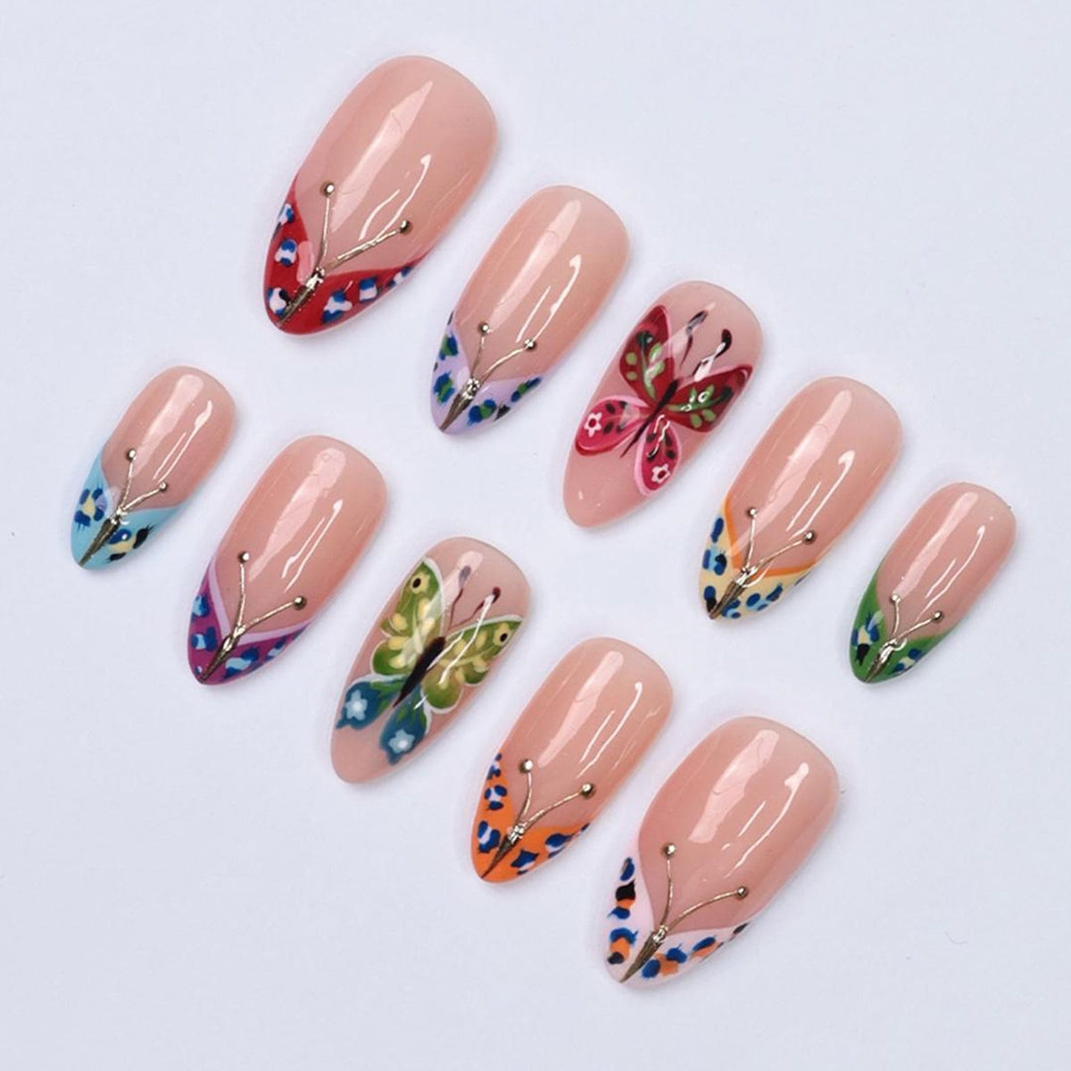 A collection of ten artificial nails with a nude base. Each nail features a butterfly design, with variations in color and style. The butterfly designs include red, pink, green, blue, and orange, with gold accents. The nails are arranged on a white s