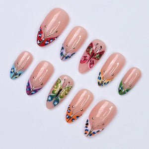 A collection of ten artificial nails with a nude base. Each nail features a butterfly design, with variations in color and style. The butterfly designs include red, pink, green, blue, and orange, with gold accents. The nails are arranged on a white s