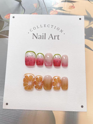 A set of press-on nails with fruit designs. The top row features watermelon designs with red, pink, and green accents. The bottom row showcases orange slice designs with gold glitter. The text "Collec