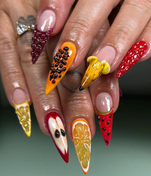 A set of long, pointed fingernails with detailed fruit designs. Each nail features a different fruit, including grapes, papaya, banana, strawberry, lemon, apple, orange, and watermelon, all painted with vibrant colors and realistic textures.