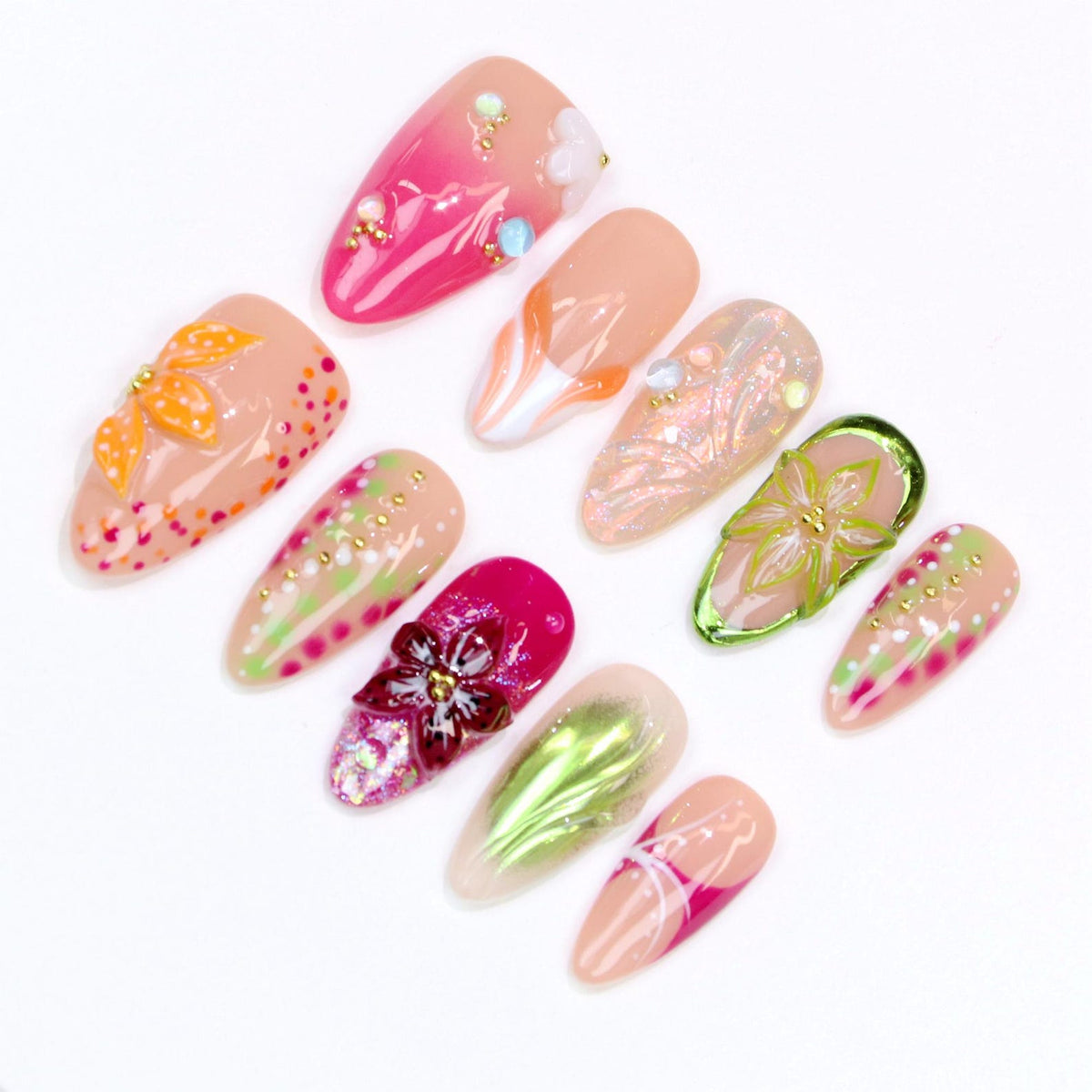 A collection of ten almond-shaped artificial nails with various designs. The nails feature a range of colors, including pink, peach, and green, with floral and abstract patterns. Some nails are adorned with small beads and glitter.