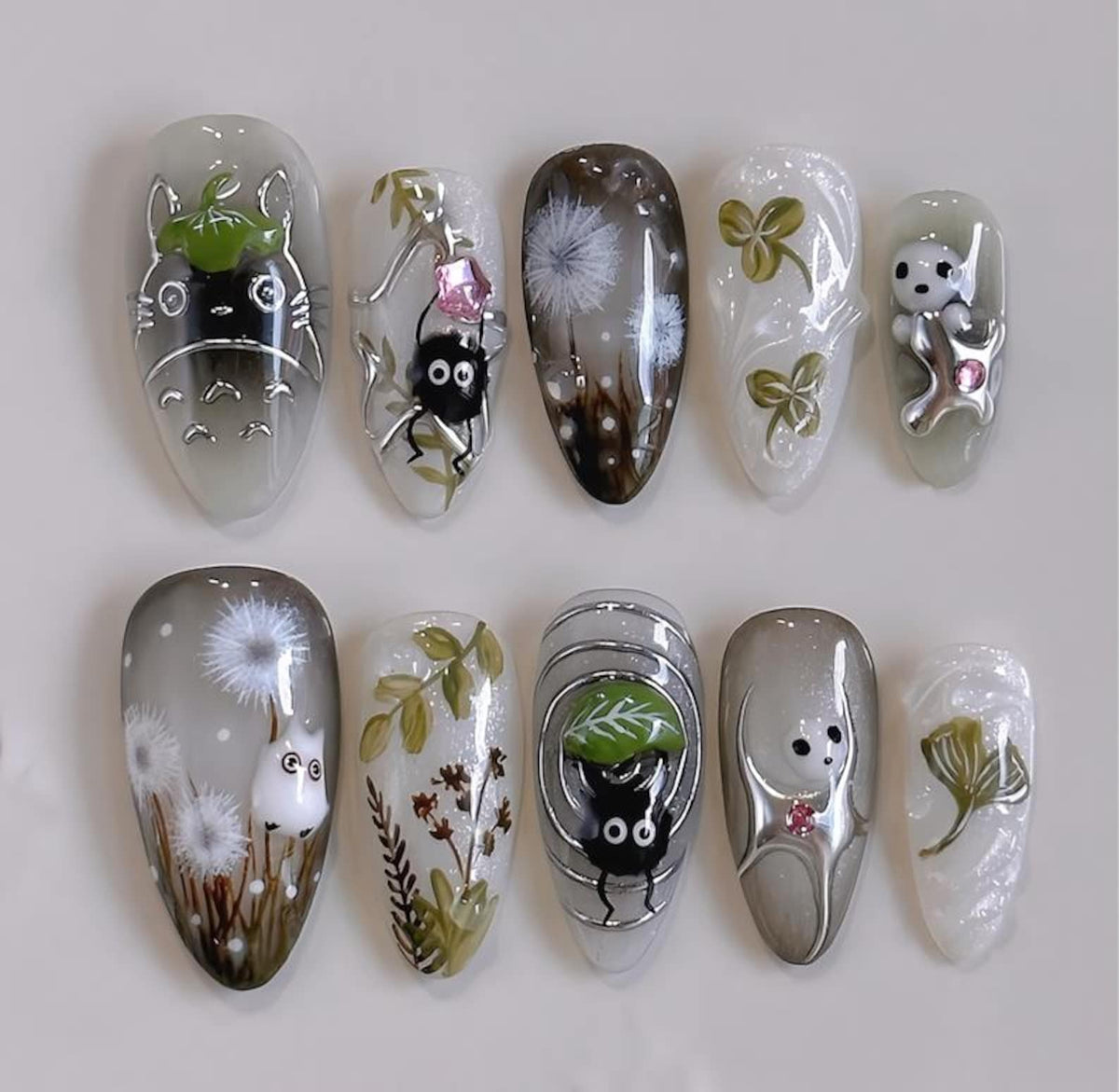 A set of ten artificial nails with various designs. The designs include cartoon characters, dandelions, and floral patterns. The nails are oval-shaped and have a glossy finish, with a variety of color