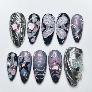 A set of ten almond-shaped artificial nails with various designs. The nails feature silver, black, and purple colors, with star, heart, and butterfly accents. Some nails have 3D embellishments, and others have glitter details.