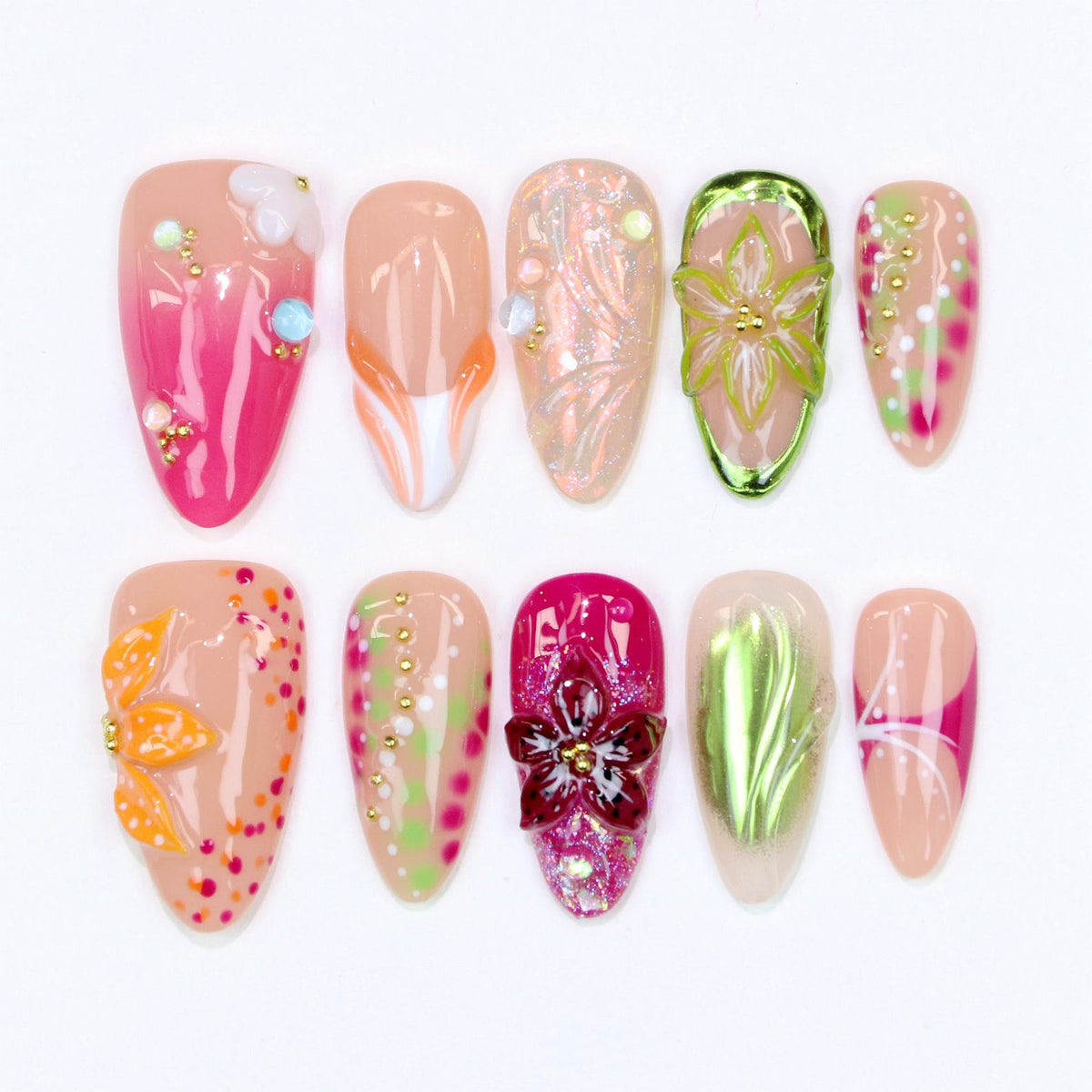 A collection of ten artificial nails in various designs. The nails feature a range of colors, including pink, orange, green, and beige, with floral and abstract embellishments. Some nails have 3D elements and glitter.