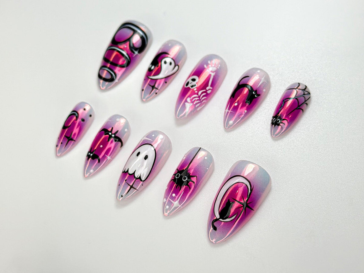 A set of ten iridescent, almond-shaped false nails. Each nail features a different Halloween-themed design in black and white, including ghosts, bats, spiders, and skeletons, set against a pink and purple gradient.