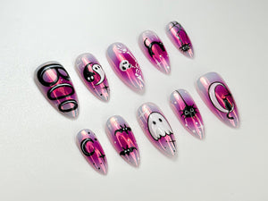 A set of ten iridescent press-on nails with a Halloween theme. Each nail features a different design, including a ghost, spider, bat, and the word "Boo". The nails have a pink and purple gradient.