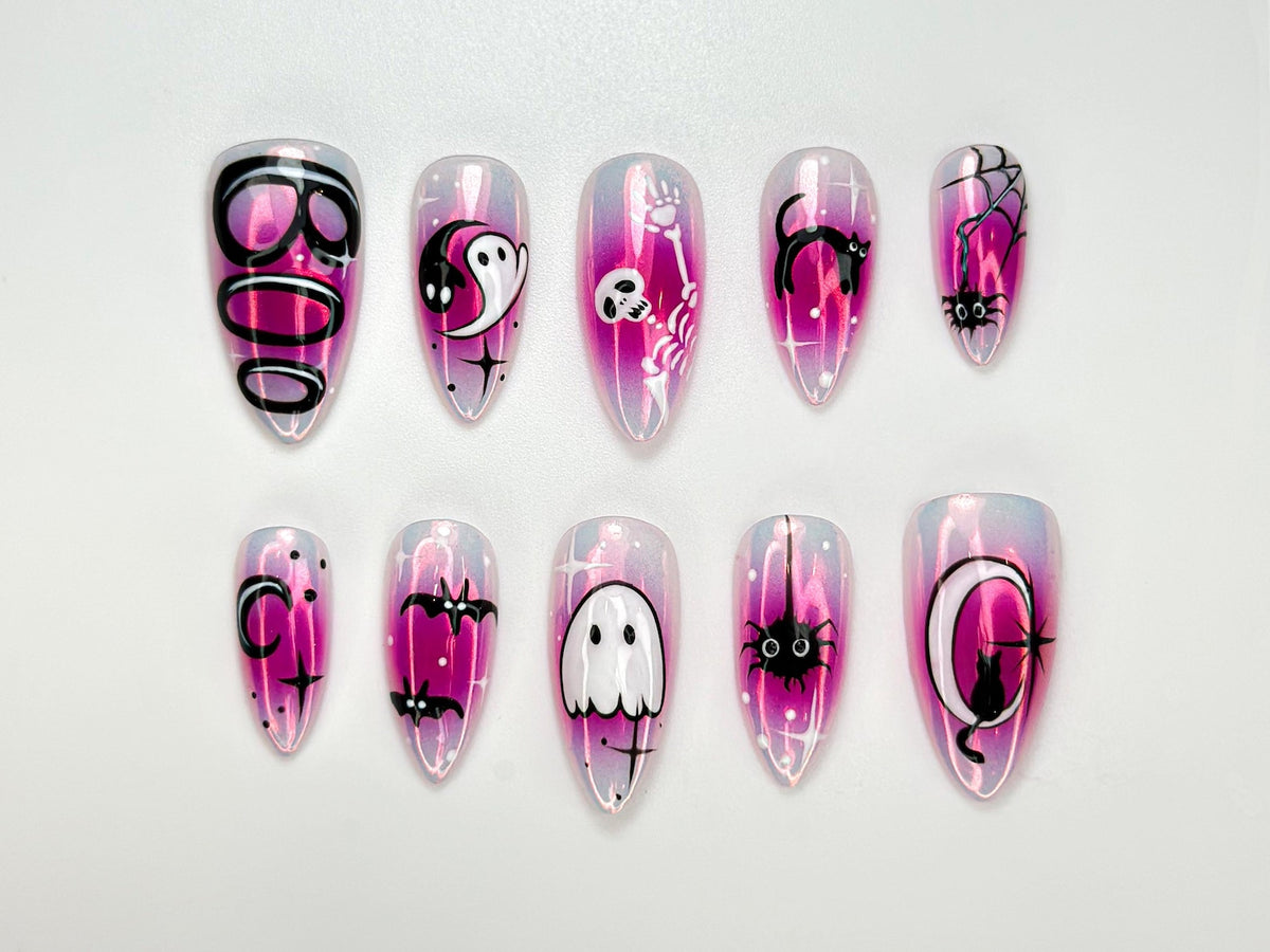 Set of ten press-on nails with a pink and iridescent finish. Each nail features Halloween-themed designs, including ghosts, bats, spiders, and the word "BOO".