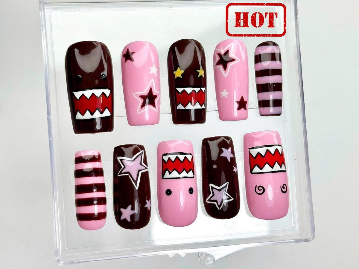 A set of ten handmade long coffin press-on nails featuring glossy pink and black designs with bold star accents, checker patterns, abstract graphics, striped details, and a salon-quality finish. Reusa