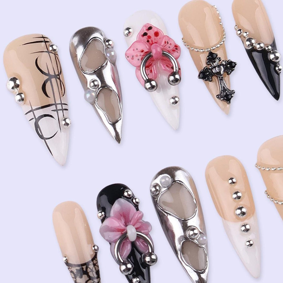 A collection of artificial nails with various designs. Some nails are nude-colored, others are white or black. Embellishments include silver metal accents, pearls, and floral designs. Some nails feature a cross or abstract patterns.