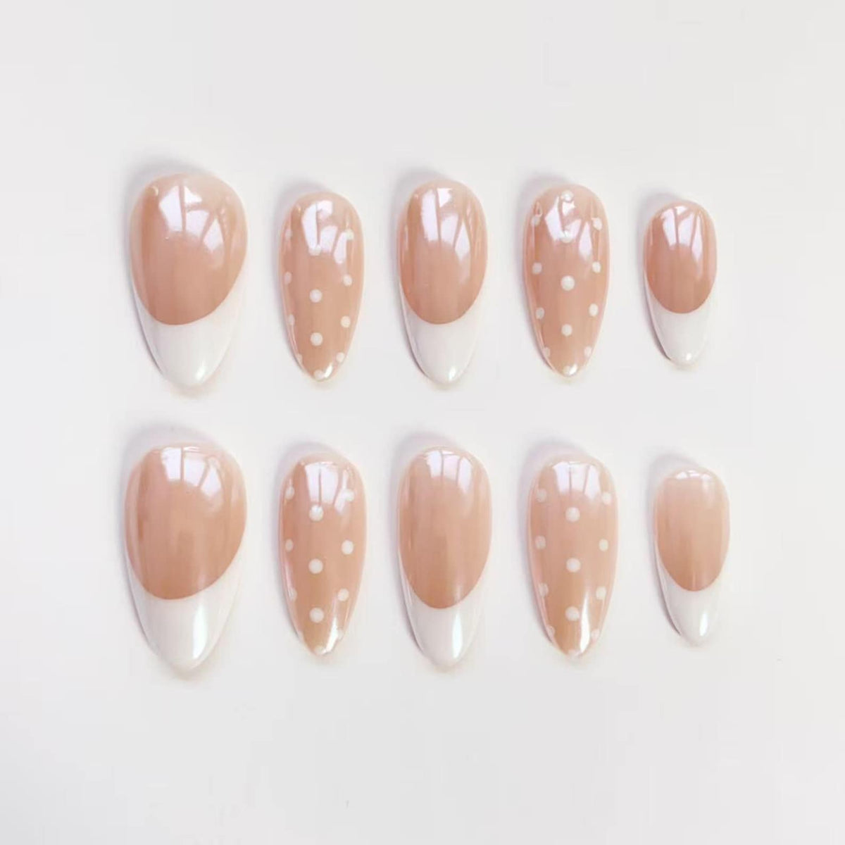 Set of ten artificial nails. Each nail features a light pink base with a white tip. Some nails have white polka dots. The nails are oval-shaped and arranged on a white surface.