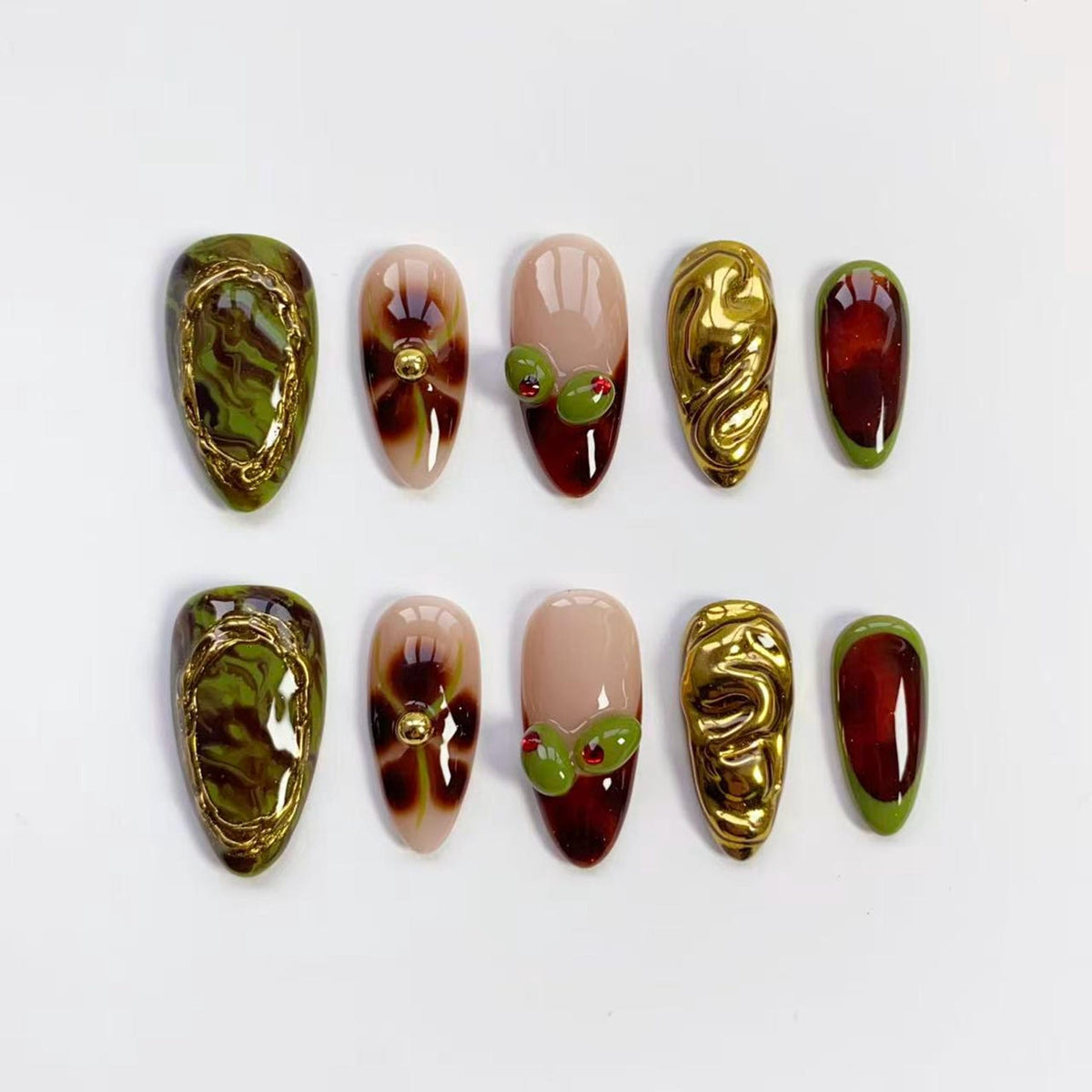 A set of ten artificial nails in various designs. The nails feature olive green, gold, and burgundy colors. Some nails have gold embellishments, while others have olive and red accents. The nails are oval-shaped.