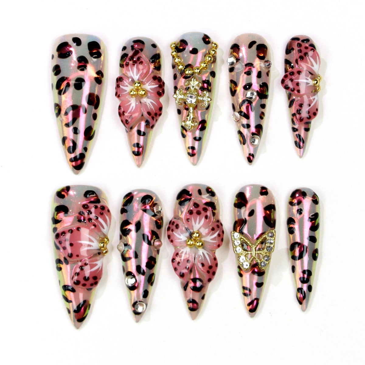 A set of ten long, pointed false nails. Each nail features a pink and black leopard print design. Some nails are adorned with 3D pink flowers, gold crosses, rhinestones, and a gold butterfly.