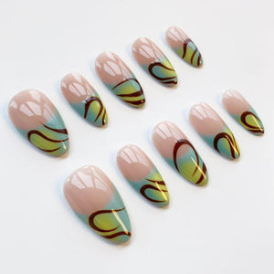 Set of oval-shaped false nails. Each nail features a nude base with a gradient of light blue and yellow-green, accented by a dark brown swirl design. The nails are arranged on a white surface.