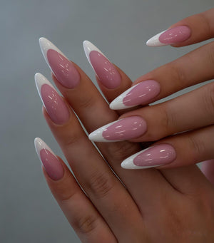 Close-up of a hand with long, almond-shaped nails. The nails feature a classic French manicure design, with a pale pink base and crisp white tips. The nails are glossy and well-manicured.