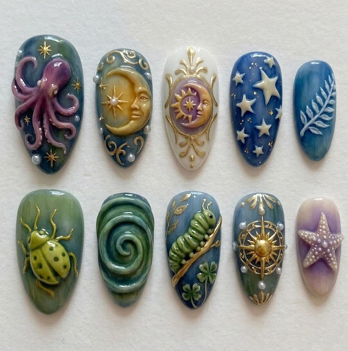 A set of ten sculpted nail art designs. Each nail features a different design, including an octopus, moon, sun, stars, fern, ladybug, spiral, caterpillar, compass, and starfish. The nails are painted in various colors with pearl accents.