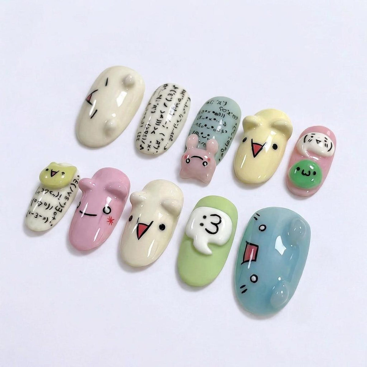 A collection of ten uniquely designed nail art pieces. Each nail features a different design, including cartoon faces, mathematical symbols, and a small bunny. The nails are painted in various pastel colors, such as pink, green, and blue.