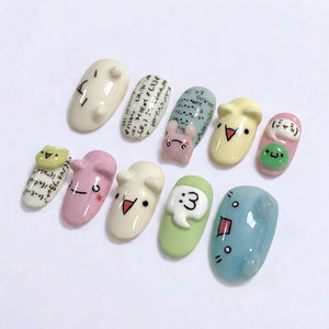 A collection of ten uniquely designed nail art pieces. Each nail features a different design, including cartoon faces, mathematical symbols, and a small bunny. The nails are painted in various pastel colors, such as pink, green, and blue.