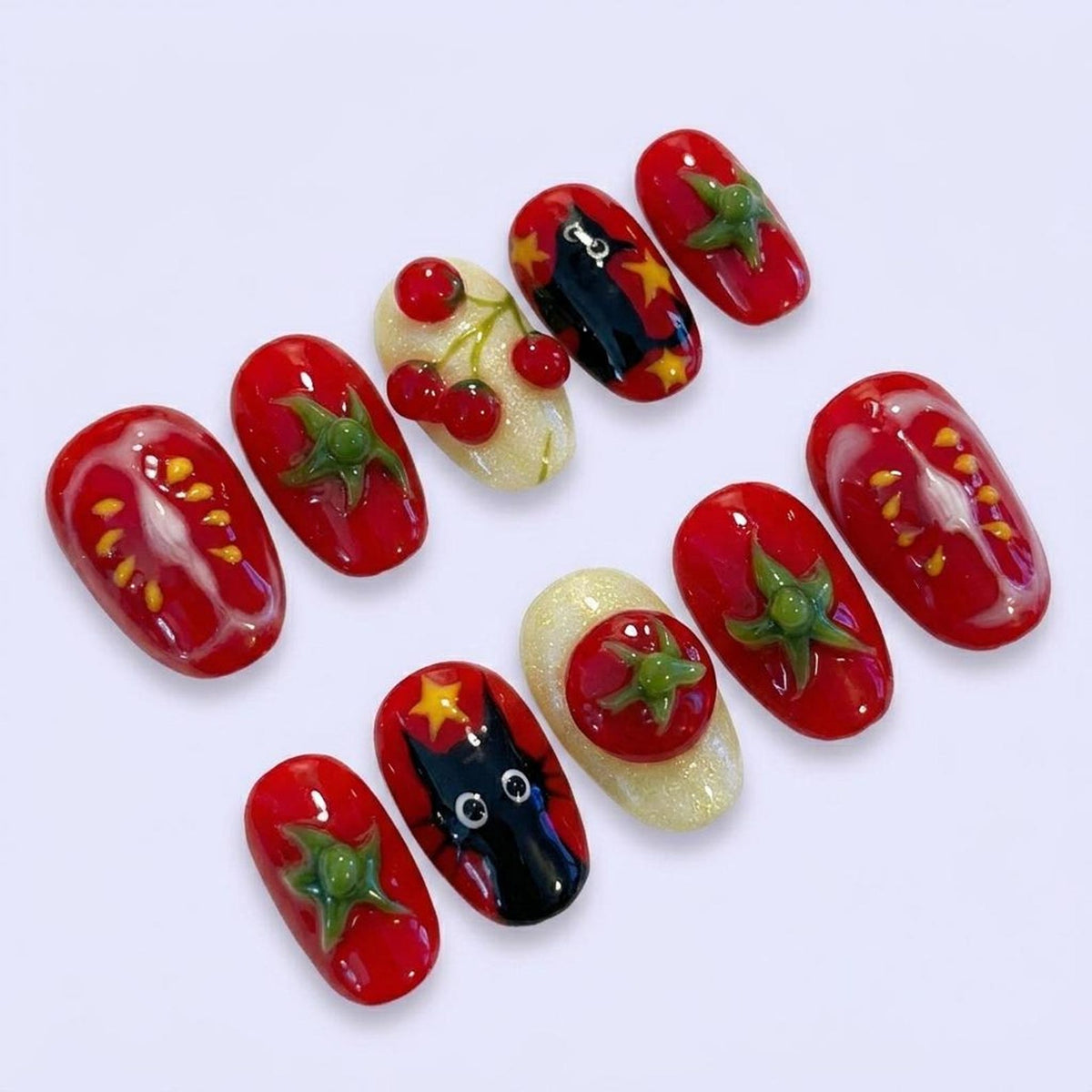 A set of ten artificial nails with a variety of designs. The nails feature a red tomato theme, with some nails showcasing tomato slices, green leaves, and cherry designs. Other nails have a black cat design.