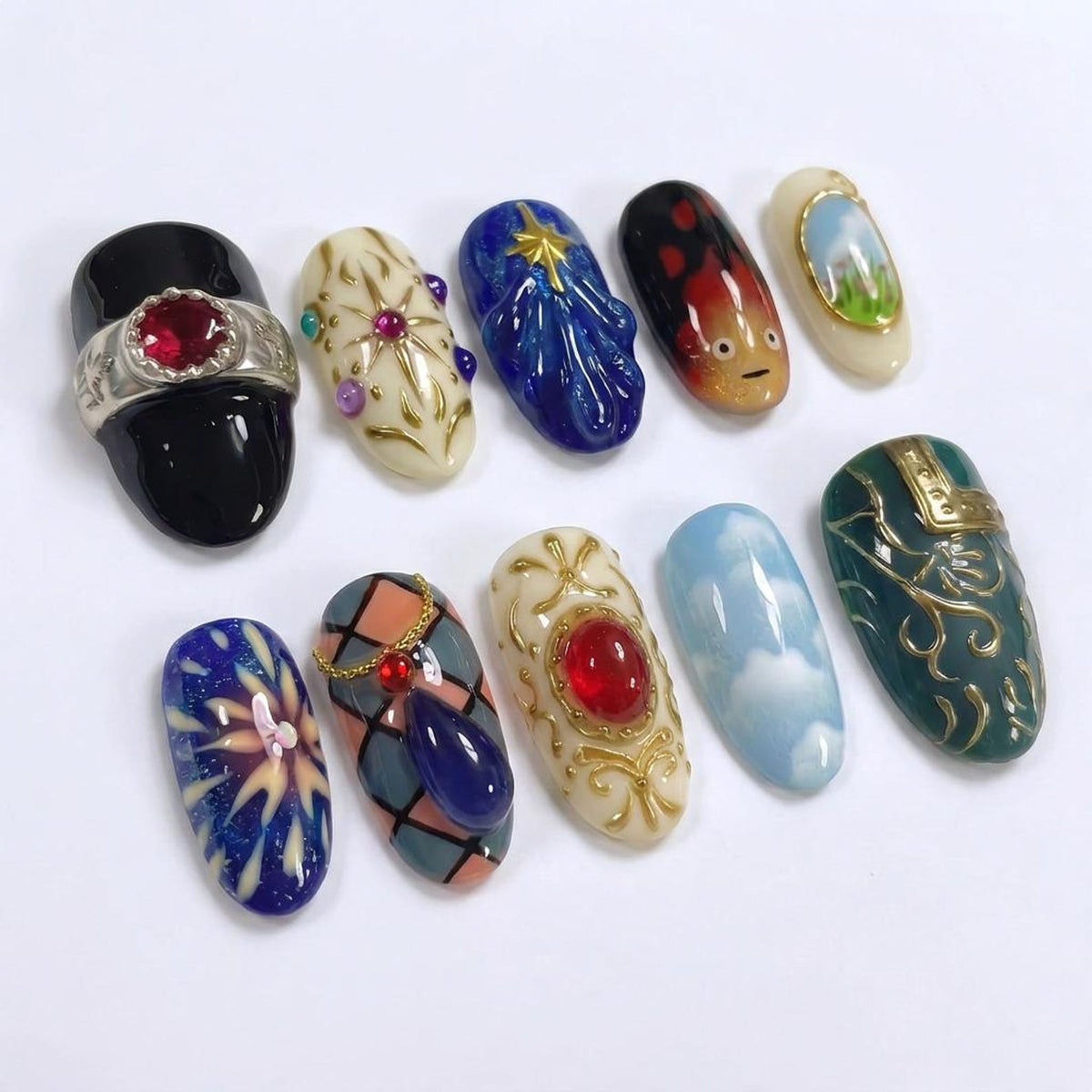 A collection of ten intricately designed nail art pieces. Each nail features unique designs, including gemstones, abstract patterns, and miniature landscapes. Colors range from deep blues and reds to soft pastels and gold accents, showcasing a variet