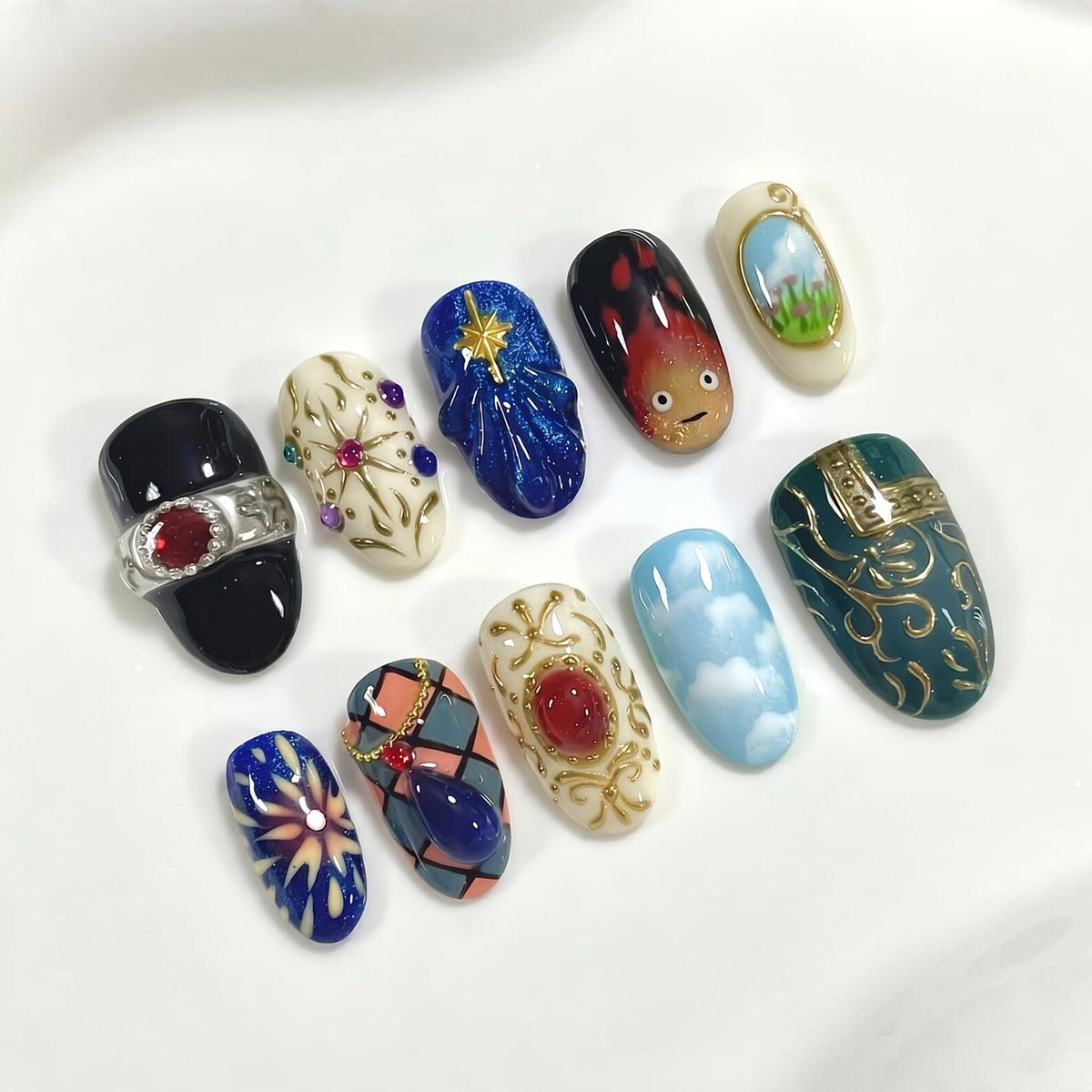 A collection of ten intricately designed nail art samples. The designs include a black nail with a silver ring and red gem, a white nail with a starburst design, and a blue nail with a gold star. Other designs feature clouds, flames, and ornate patte